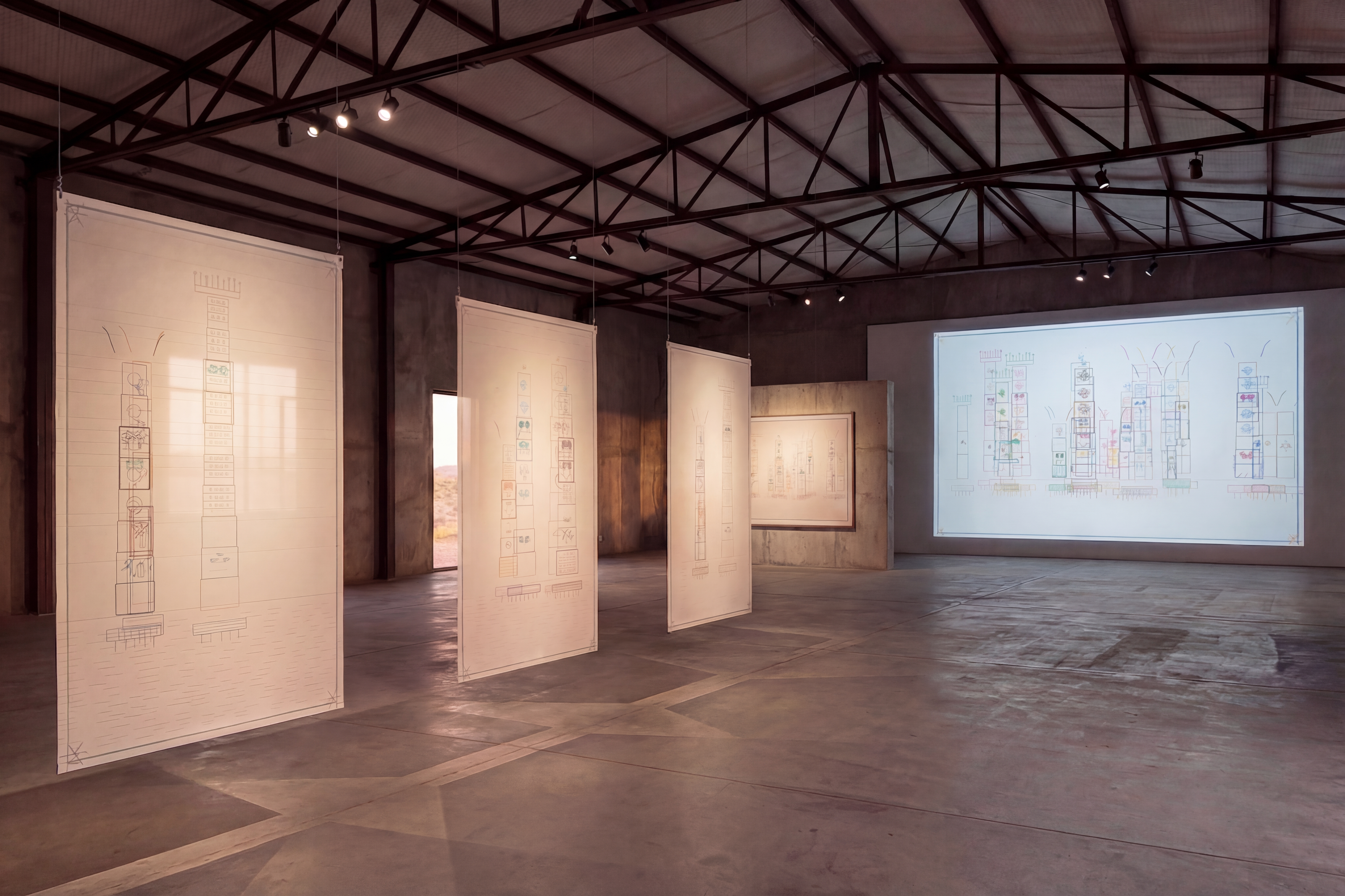 Warehouse installation study — DATASPHERE projected on a gallery wall with suspended architectural paper panels and a framed DATASPHERE work in the background